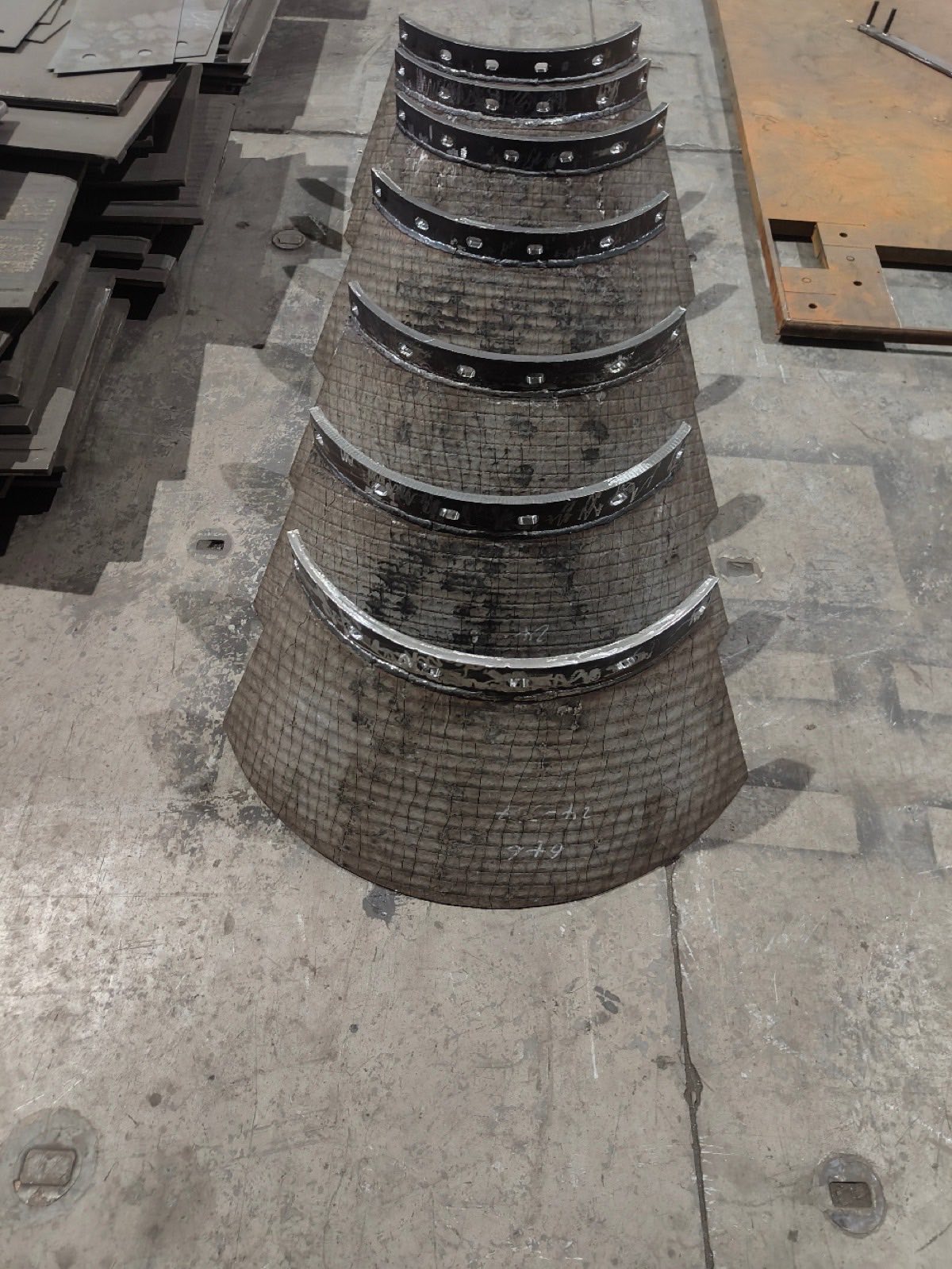 Set of curved cone-segment wear liners laid out in the workshop